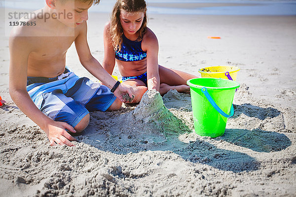 Geschwister spielen mit Sand am Strand