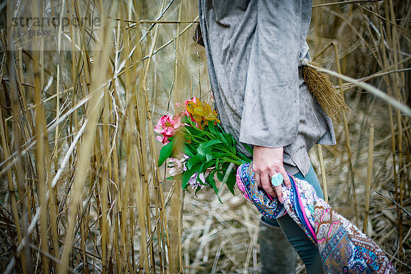 Frau mit Blumen im hohen Gras