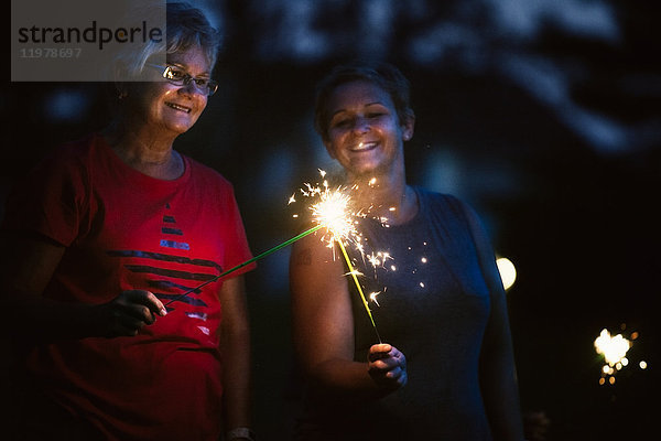 Ältere und reife Frau zünden am Unabhängigkeitstag nachts gemeinsam Wunderkerzen an  USA