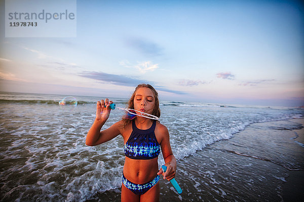 Mädchen bläst Seifenblasen am Strand