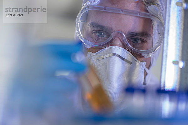 Laborant  der ein mit Flüssigkeit gefülltes Reagenzglas hält  Nahaufnahme
