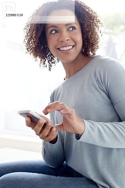 Mittlere erwachsene Frau  die ein Mobiltelefon benutzt.