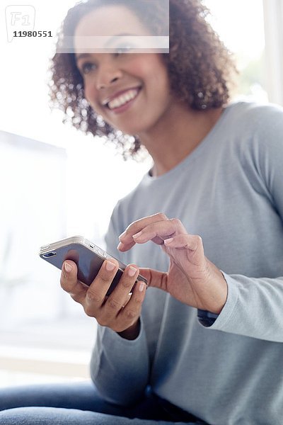 Mittlere erwachsene Frau  die ein Mobiltelefon benutzt.