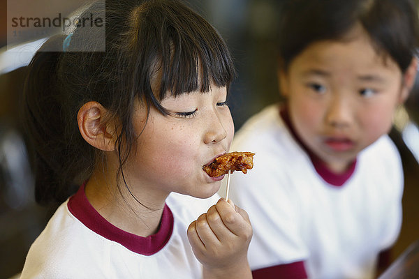 Japanische Grundschulkinder beim Essen im Klassenzimmer