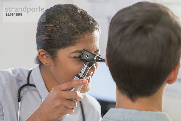 Ärztin mit Otoskop im Ohr eines Patienten