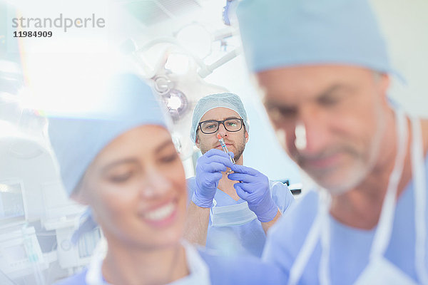 Männlicher Anästhesist bereitet Anästhesie-Medikamente in einer Spritze im Operationssaal vor