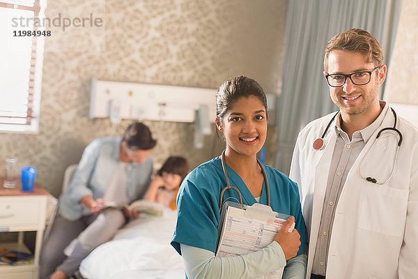 Porträt eines lächelnden  selbstbewussten Arztes und einer Krankenschwester bei der Visite in einem Krankenhauszimmer