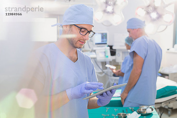 Männlicher Chirurg verwendet digitales Tablet im Operationssaal