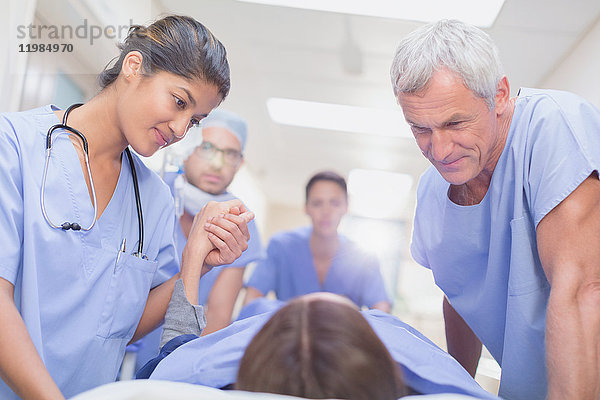 Pflegende Chirurgen im Gespräch mit einem Patienten auf einer Bahre im Krankenhausflur