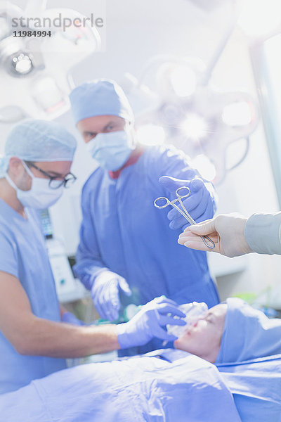 Chirurg greift im Operationssaal nach einer chirurgischen Schere