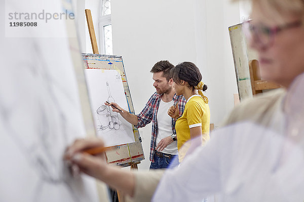 Künstler diskutieren Skizze an der Staffelei im Atelier der Kunstklasse