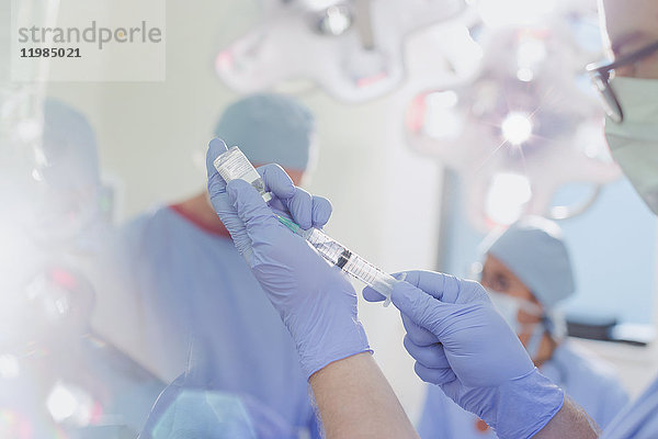 Männlicher Anästhesist mit Spritze bei der Vorbereitung von Narkosemitteln im Operationssaal
