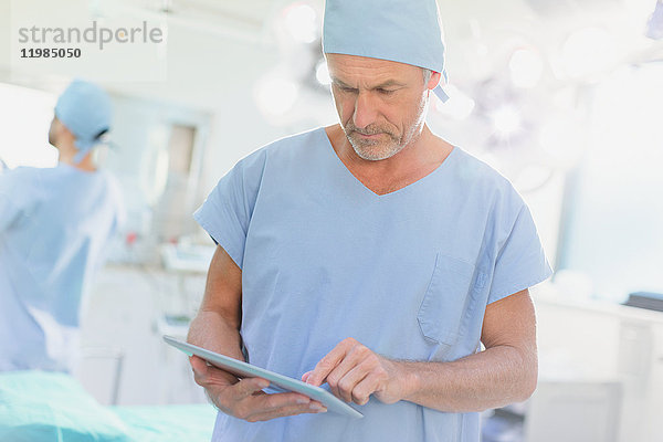 Männlicher Chirurg verwendet digitales Tablet im Operationssaal