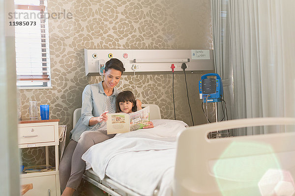 Mutter liest mit ihrer Tochter im Krankenhauszimmer ein Buch