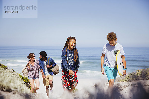 Familienwanderung mit Boogie-Board am sonnigen Sommerstrand des Ozeans