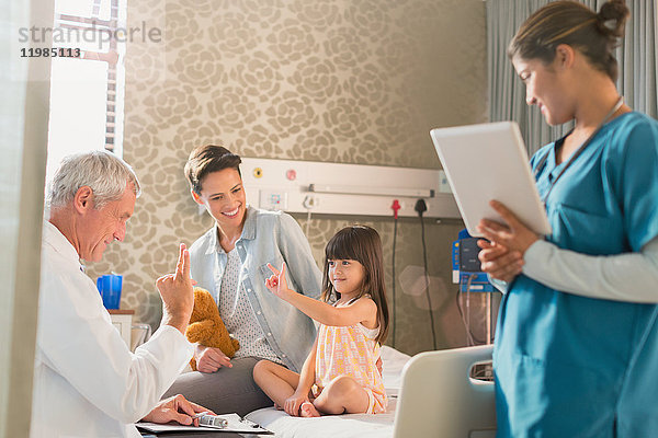 Arzt macht Visite  gestikuliert mit Patientin im Krankenhauszimmer