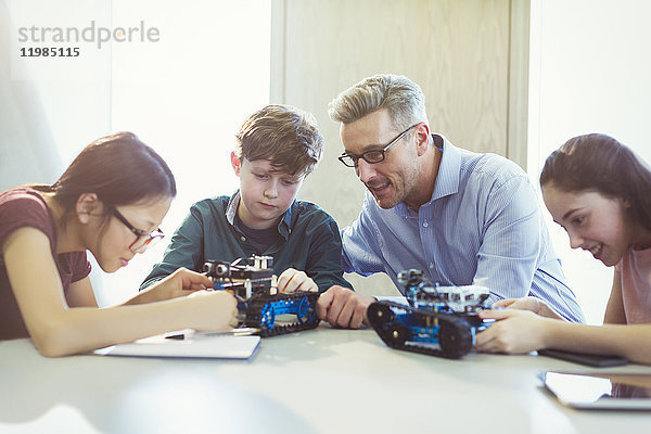 Lehrer hilft Schülern beim Zusammenbau von Robotern im Klassenzimmer