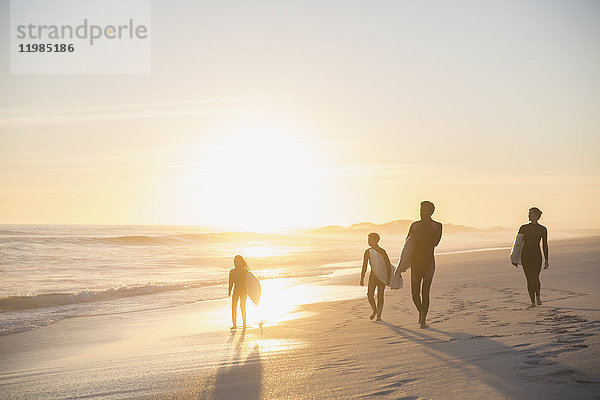 Silhouette Familien-Surfer wandern mit Surfbrettern am idyllischen  sonnigen Sommer-Sonnenuntergangsstrand
