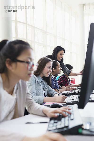 Lehrerin hilft Schülern  die an Computern im Computerlabor arbeiten