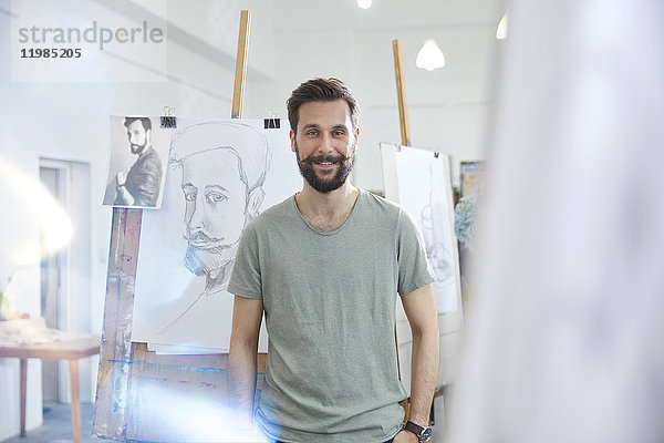 Porträt lächelnder  selbstbewusster Künstler beim Zeichnen im Atelier der Kunstklasse