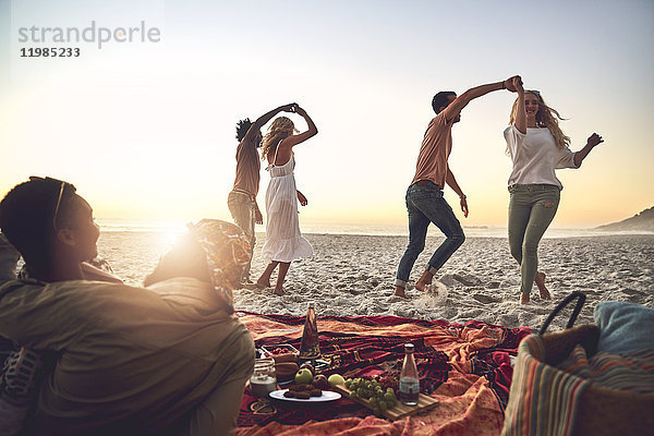 Junge Paare tanzen  genießen Picknick am Sommerstrand