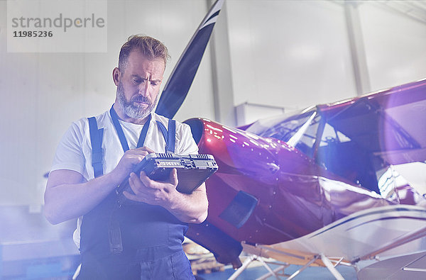 Mechaniker bei der Diagnose mit Geräten in der Nähe des Flugzeugs im Hangar