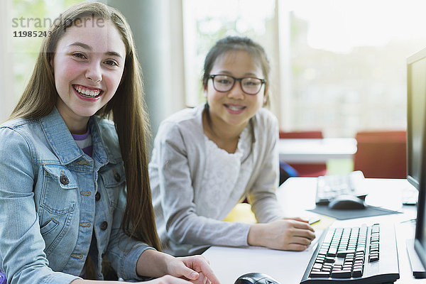 Portrait lächelndes  selbstbewusstes Mädchen  das am Computer in der Bibliothek forscht.