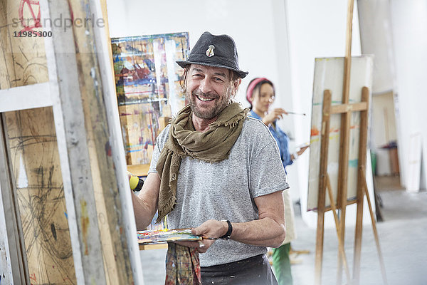 Portrait lächelnde männliche Malerei an der Staffelei im Atelier der Kunstklasse