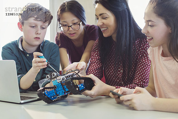 Lehrerin und Schülerinnen beim Programmieren und Montieren von Robotern im Unterricht