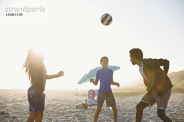 Familie spielt Fußball am sonnigen Sommerstrand
