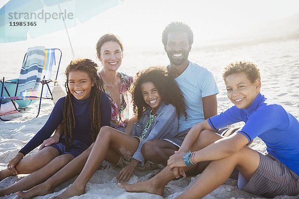 Portrait lächelnde multiethnische Familie am sonnigen Sommerstrand