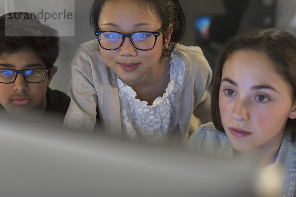 Fokussierte Schüler mit Computer im dunklen Klassenzimmer