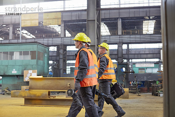 Männliche Arbeiter  die in der Stahlfabrik spazieren gehen