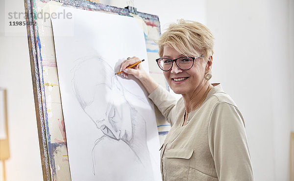 Portrait lächelnde Künstlerin beim Skizzieren an der Staffelei im Atelier