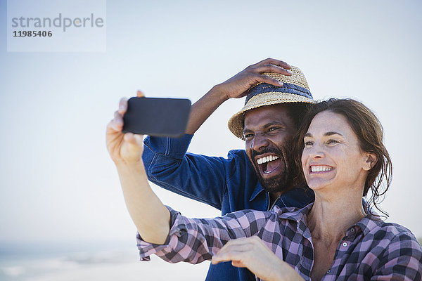 Lachendes  enthusiastisches multiethnisches Paar  das Selfie mit Fotohandy nimmt.