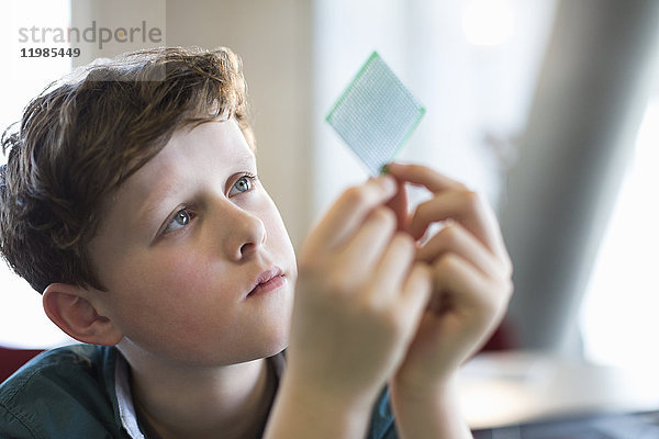 Neugieriger  fokussierter Junge untersucht Computerchip im Klassenzimmer