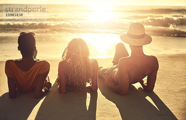 Unbeschwerte junge Freunde  die sich am sonnigen Sommer-Sonnenuntergang am Meer entspannen.