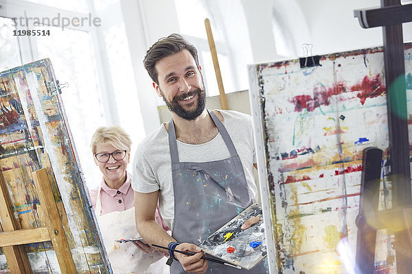 Portrait lächelnde Künstler malen an Staffeleien im Atelier der Kunstklasse