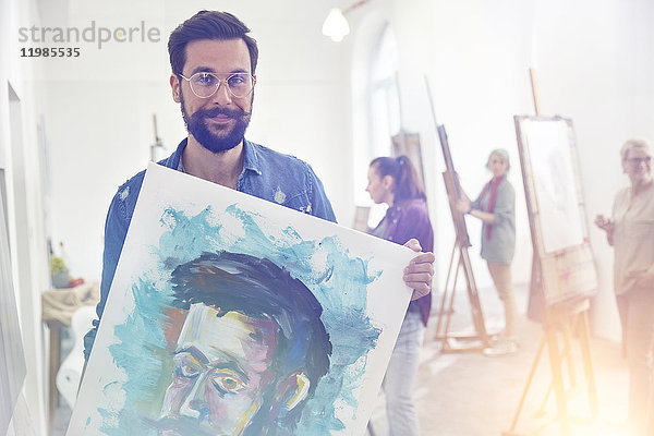 Portrait lächelnder  selbstbewusster  stolzer Künstler mit Malerei im Atelier der Kunstklasse