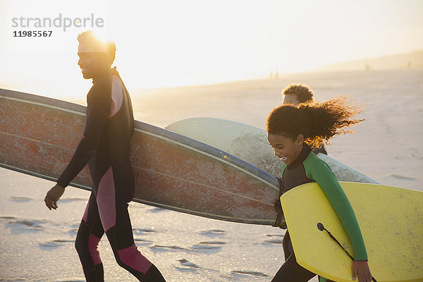Familie mit Surfbrettern und Boogie-Boards am sonnigen Sommerstrand