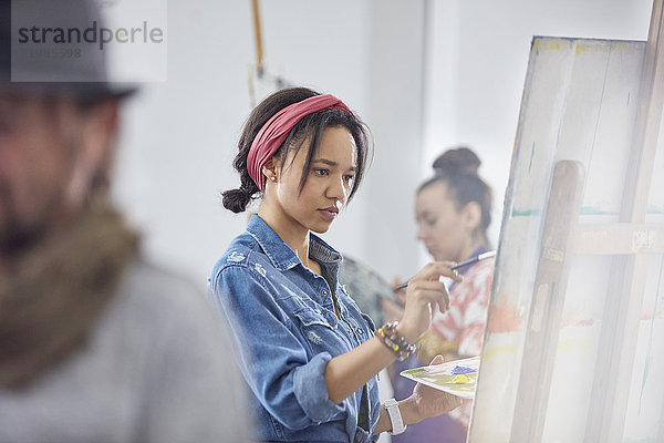 Fokussierte Künstlerin an der Staffelei im Atelier der Kunstklasse