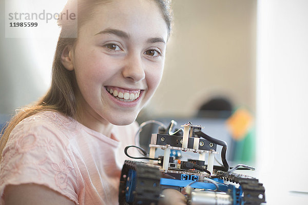 Portrait lächelndes  selbstbewusstes Mädchen  das einen Roboter hält