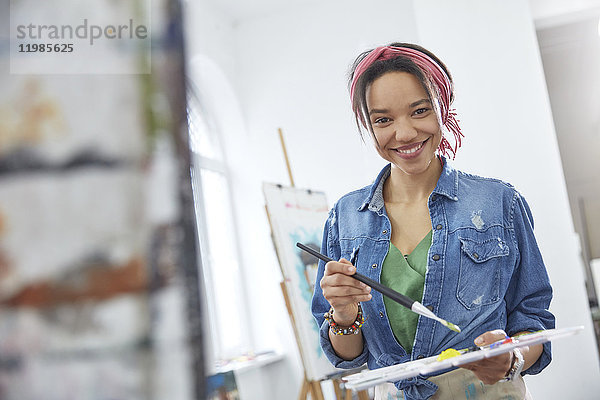 Portrait lächelnde Künstlerin mit Pinsel und Palette  Malerei im Atelier der Kunstklasse