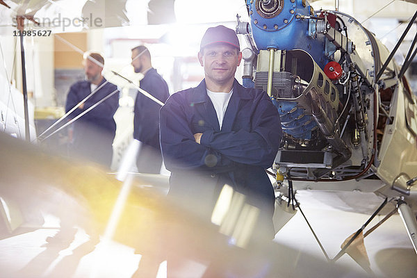 Portrait selbstbewusster Mechaniker bei der Arbeit am Flugzeug im Hangar