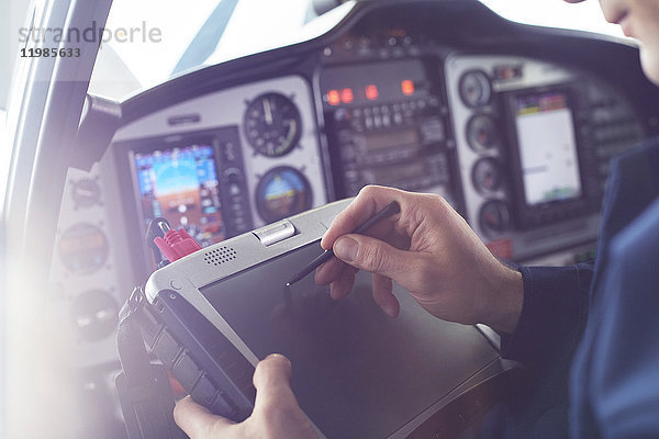 Flugzeugpilot mit Stylus auf digitalem Tablett im Cockpit