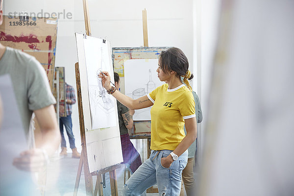 Künstlerin beim Skizzieren an der Staffelei im Atelier der Kunstklasse