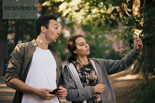 Fröhliche Frau nimmt Selfie mit männlichem Freund von Smartphone