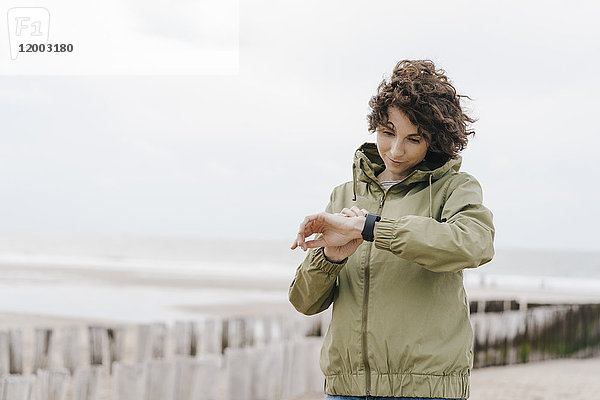 Die Frau am Strand schaut auf ihre Smartwatch.