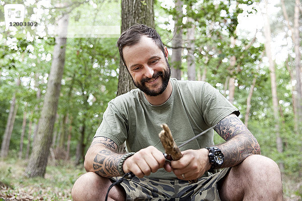 Lächelnder Mann beim Schnitzen im Wald