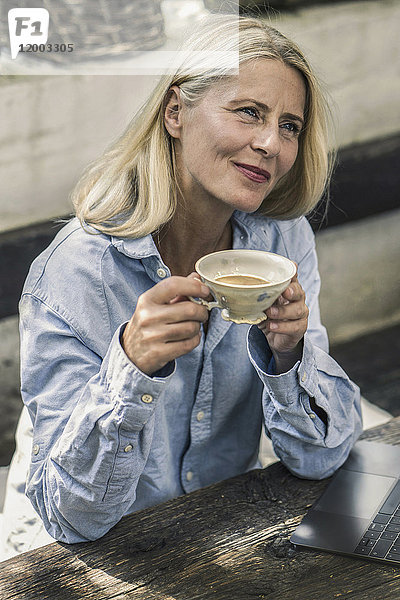 Reife Frau auf der Terrasse sitzend  Tee trinkend